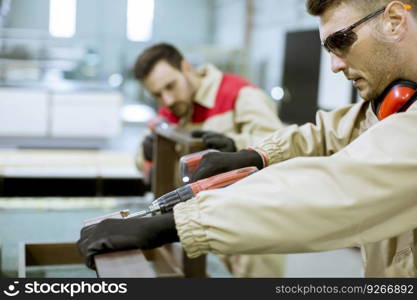 Two handsome young workers assembling furniture in the factory