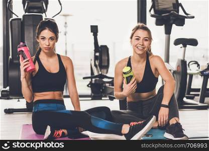 Two happy and cute girls resting after workout at the gym