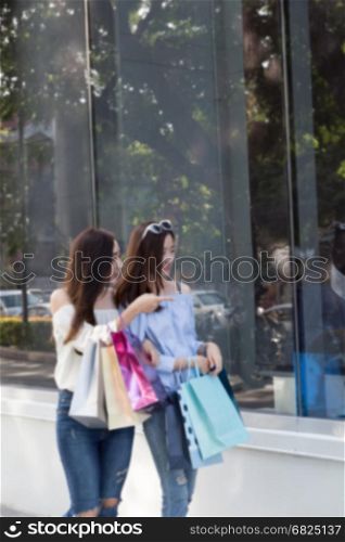 two happy asian shopaholic women with colorful shopping bags at department store shopping mall, blur background