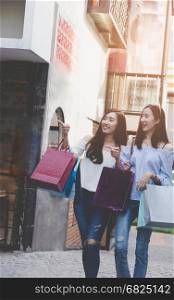two happy asian shopaholic women with colorful shopping bags at department store shopping mall