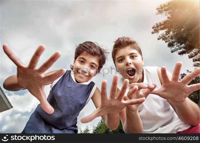 Two happy boys having fun outdoors, making faces to the camera, best friends enjoying holidays in a summer camp