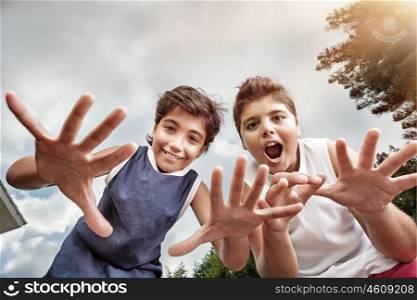 Two happy boys having fun outdoors, making faces to the camera, best friends enjoying holidays in a summer camp