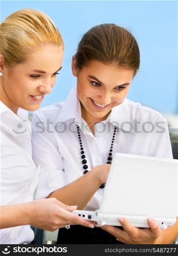 two happy businesswomen with laptop computer (focus on blonde)
