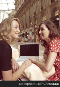 two happy businesswomen with laptop computer in the city