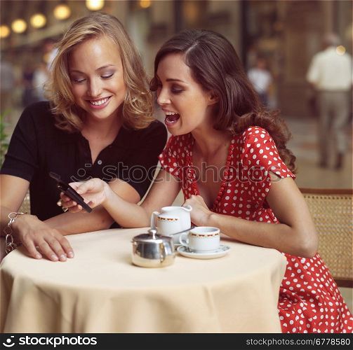 two happy businesswomen with mobile phone in the city