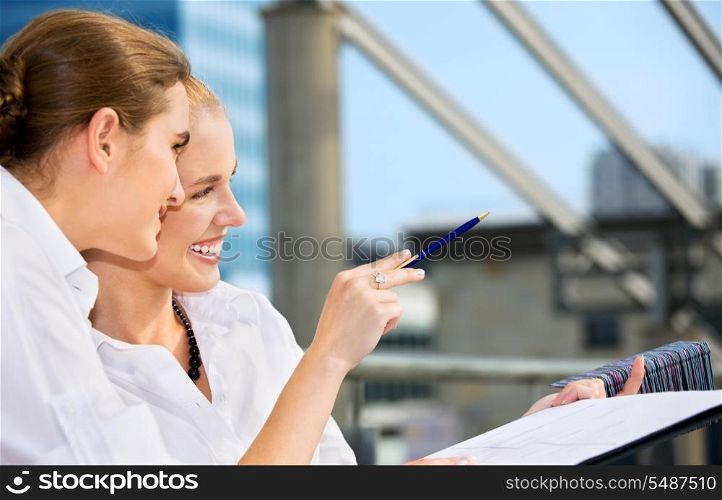 two happy businesswomen with paper chart (focus on blonde)