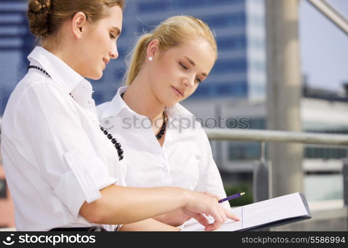 two happy businesswomen with paper chart (focus on brunette)