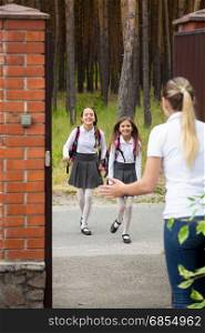 Two happy cheerful girls running to their mother after school