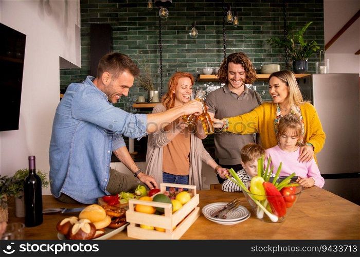 Two happy families toasting with cider while preparing dinner in the kitchen