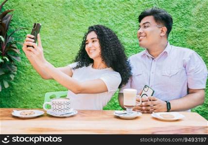 Two happy friends having a coffee and taking a selfie. Couple of friends sitting enjoying a coffee and taking a selfie