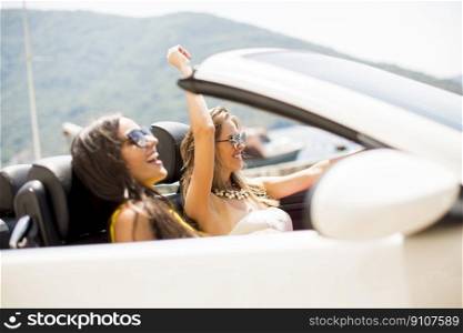 Two happy friends in white cabriolet car driving everywhere and looking for freedom and fun