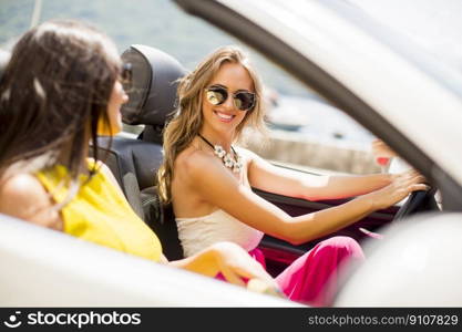 Two happy friends in white cabriolet car driving everywhere and looking for freedom and fun