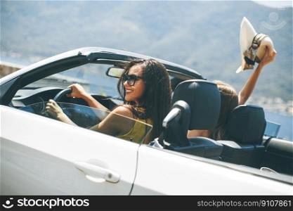 Two happy friends in white cabriolet car driving everywhere and looking for freedom and fun