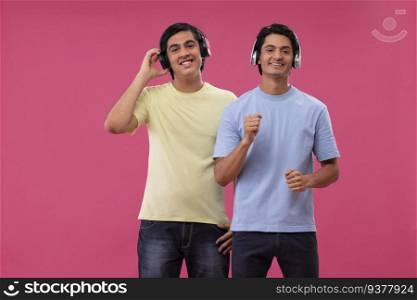 Two happy friends listening toμsic againstπnk background