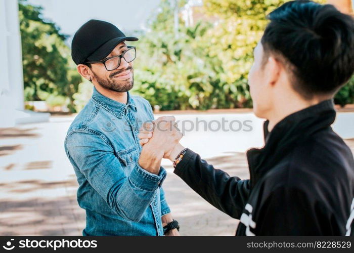 Two happy friends shaking hands in the street. Two people shaking hands on the street. Two smiling friends greet each other on the street