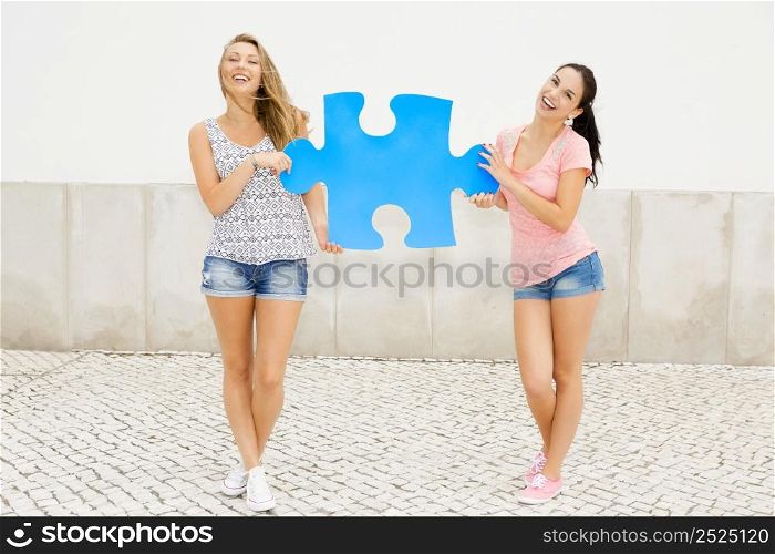 Two happy girls holding a giant puzzle piece