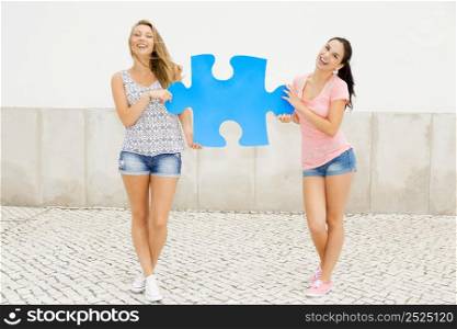 Two happy girls holding a giant puzzle piece