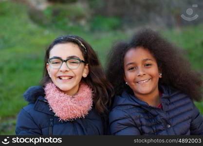 Two happy girls in the park with coats