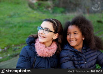 Two happy girls in the park with coats