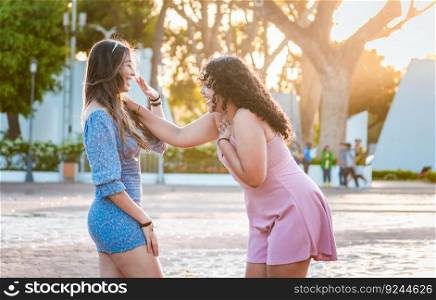 Two happy girls laughing in the street. Happy female friends laughing in the street. Concept of happy female friends chatting in the street