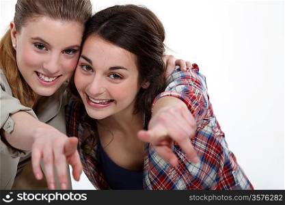 Two happy girls pointing at the camera