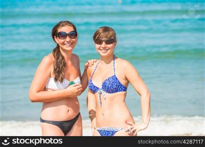 Two happy girls resting on the beach