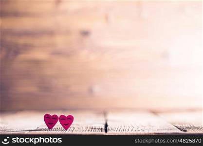 Two happy hearts. Two pink happy smiling hearts on wooden background