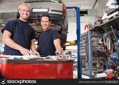 Two happy mechanics standing in garage