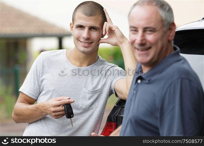 two happy men outside car