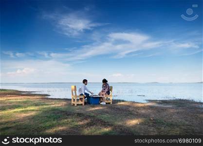 Two happy siblings playing a game with chess near the lake in nature. children playing a game with chess