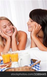 Two happy women having breakfast in bed together