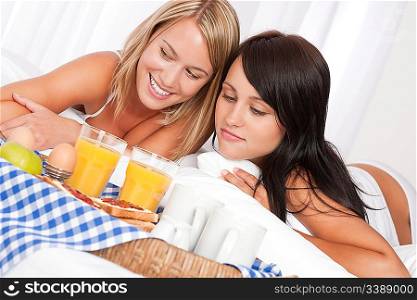 Two happy women having home made breakfast in the bedroom