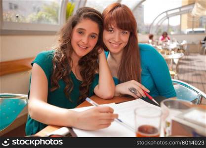 Two happy young beautiful women studying