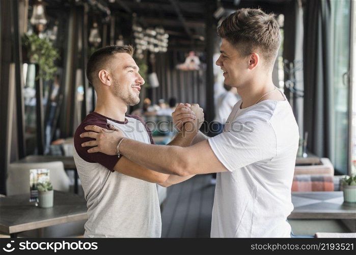two happy young male friends shaking hands restaurant