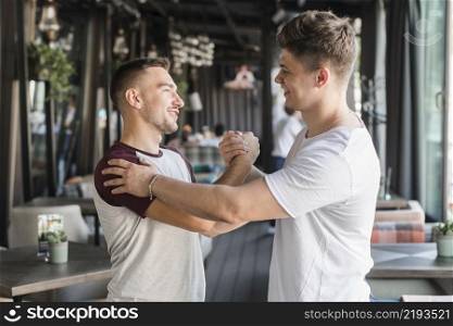two happy young male friends shaking hands restaurant