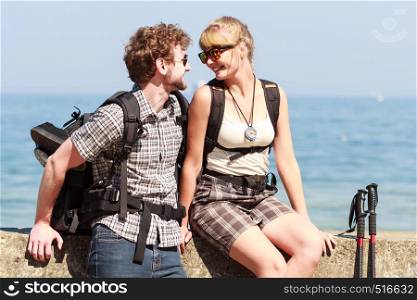 Two happy young people tourists hiking by sea ocean water. Backpackers couple on summer vacation trip journey.. Two people tourists hiking by sea ocean.