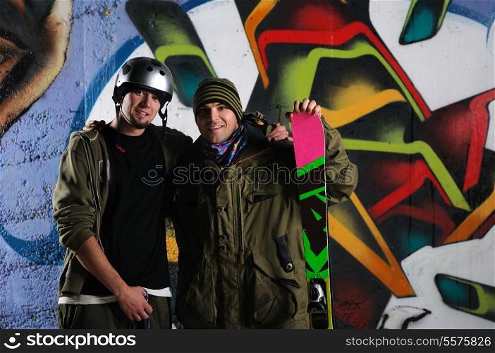 two happy young skiirs standing against colorful background