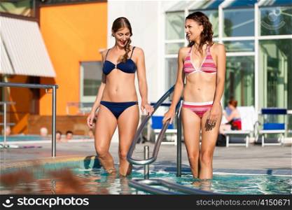 Two happy young women wading water in hydrotherapy in a health spa
