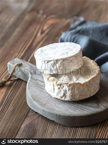 Two heads of Camembert on the wooden board
