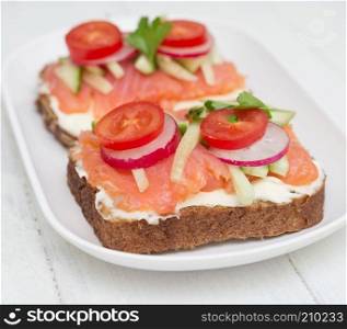 Two healthy open sandwiches in plate on wooden background