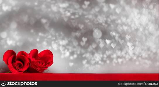 Two heart shaped red roses on fabric over glitter background, Valentines day