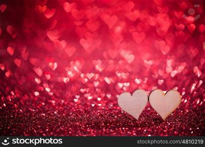 Two hearts on glitters. Two wooden hearts on red glowing bokeh hearts background for Valentines day