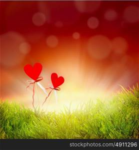 Two hearts on grass and sky background with bokeh, abstract love concept