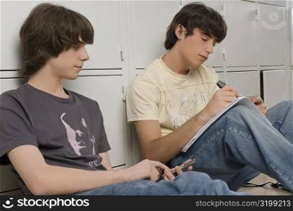 Two high school students studying in front of lockers