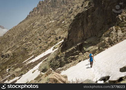 Two hikers and two dogs traversing the snow in the mountains of Restonica near Lac de Melo