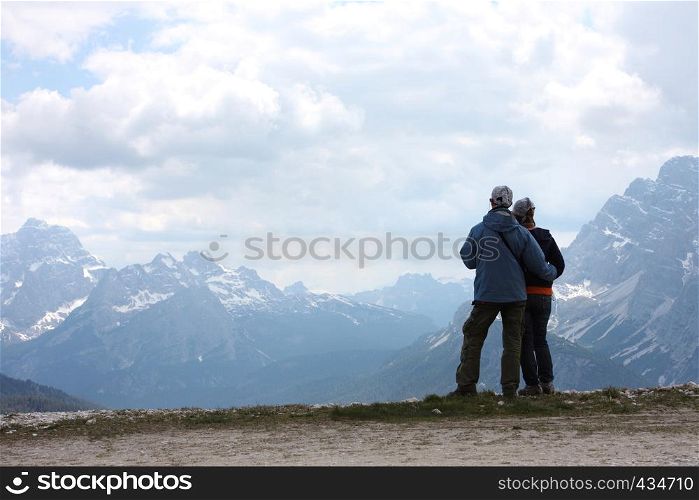 two hikers are standing on a rock and looking at the mountains