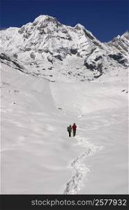 Two hikers standing in a snow covered landscape, Annapurna Range, Himalayas, Nepal