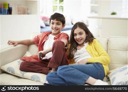 Two Hispanic Children Sitting On Sofa Watching TV Together