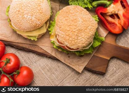 Two homemade vegetarian burgers with fresh organic vegetables on rustic wooden background. Top view with copy space.