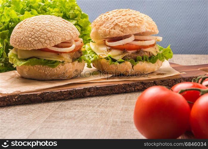 Two homemade vegetarian burgers with fresh organic vegetables on rustic wooden background